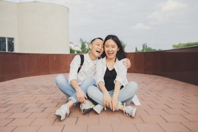 young asian couple walks in the city park. emotional portrait of students. young girl and guy brunette having fun on valentine's day. concept: 14 february