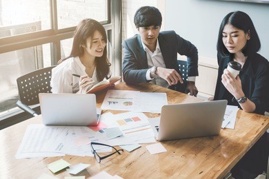 group of asian business people with casual suit are working with a financial for marketing in the modern office or coffee shop, business marketing concept.