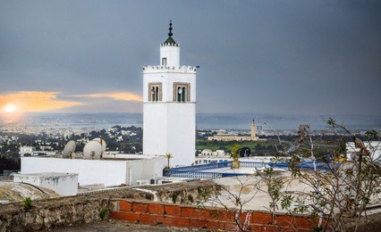 tunisian mosque (rooftop) and tower in sidi bou said at sunset, with the capital city in the distance - tunis, tunisia [africa]  