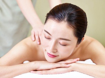close-up of face of a beautiful young asian woman lying on front on bed receiving massage in spa salon.