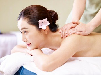 side view of a beautiful young asian woman receiving massage in spa salon.