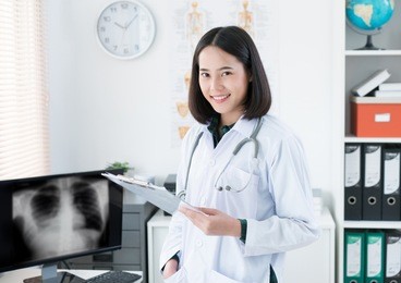 the doctor is sitting in the room to see the patient. she is opening x-ray effects.