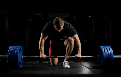 professional athlete bent over the barbell and is preparing to lift a very heavy weight. front view