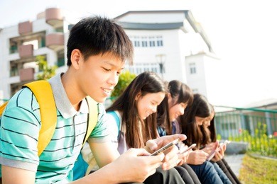 teenage studentsÂ sitting and using smart phone