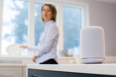 woman in kitchen asking digital assistant whilst washing up