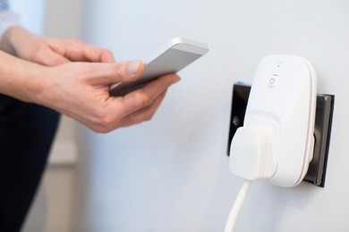 woman controlling smart plug using app on mobile phone