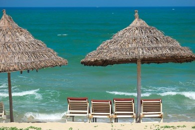 beach umbrellas and deck chairs in front of the my khe beach in da nang, vietnam.