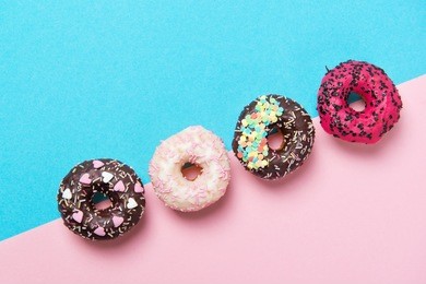 assorted colored donuts in a row, minimalism on a blue and pink background, top view
