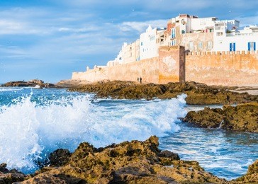 atlantic ocean waves under the walls of moroccan city of essaouira with dramatic sunset sky and selective focus