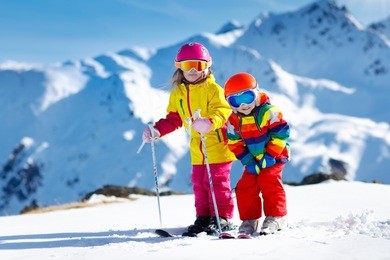 child skiing in the mountains. kid in ski school. winter sport for kids. family christmas vacation in the alps. children learn downhill skiing. alpine ski lesson for boy and girl. outdoor snow fun.