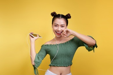 colorful studio portrait of happy young asian woman with earphones is dancing and singing.