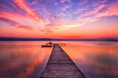 exciting sunset at shore with wooden pier and boat