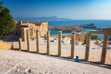 woman sitting on staircase of the propylaea on the acropolis of lindos (rhodes, greece)