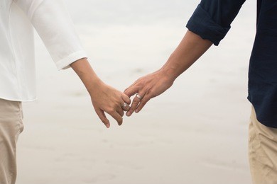 a couple holding hands at beach.