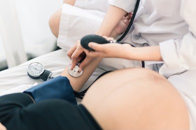 female obstetrician doctor  measuring blood pressure of the pregnant woman in the hospital. pregnancy-induced hypertension concept.
