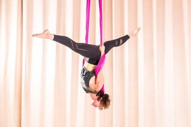 asian woman training in a fitness room with fly yoga elements