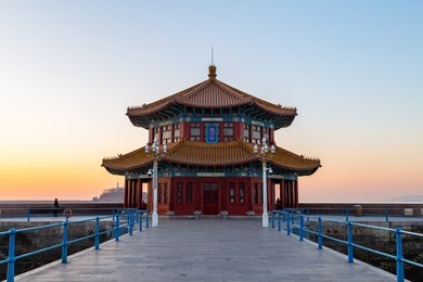 zhanqiao pier at sunrise, qingdao, shandong, china. the name "huilan pavilion" is engraved above the entrance door.