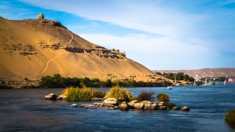 egypt. the nile at aswan and the west bank with tombs of the nobles (from the old and middle kingdom). there is qubbet el-hawa - 'dome of the winds' (tomb of a muslim prophet) at the crest of the hill