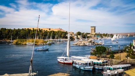 colorful landscape with boats on a busy river. nile river in aswan with tourist boats, feluccas and yachts