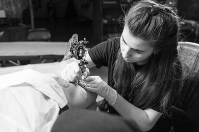 beautiful dark-haired woman tattoo artist drawing a tattoo for a tattoo, close-up, bottom view