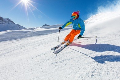 skier skiing downhill during sunny day in high mountains