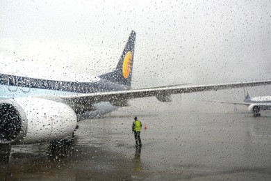 flight stranded during rain and bad weather in mumbai airport, india. airport staff standing looking at the clouds.