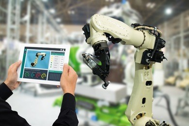 iot industry 4.0 concept,industrial engineer using software (augmented, virtual reality) in tablet to monitoring machine in real time.smart factory use automation robot arm in automotive manufacturing