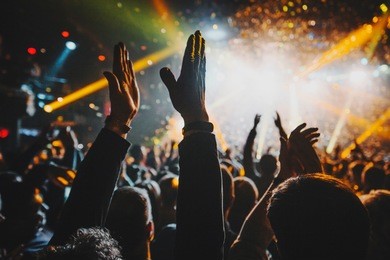 shiny rainbow confetti during the concert and the crowd of people silhouettes with their hands up