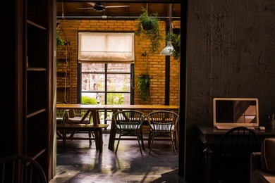 loft space design, wooden table, concrete flooring, brick wall, live plants. industrial creative minimalistic cafe interior, simplicity concept, warm brown yellow colors