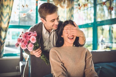 the man make a surprise with flowers for a woman in the restaurant