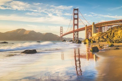 classic panoramic view of famous golden gate bridge seen from scenic baker beach in beautiful golden evening light on a sunny day with blue sky and clouds in summer, san francisco, california, usa