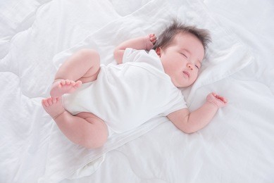 little asian infant sleeping on white bed in the morning