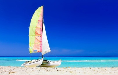the tropical beach of varadero in cuba with a colorful sailboat catamaran on a summer day with turquoise water