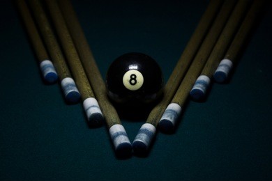 eight ball on green billiard table with cue sticks on v shape, stylish billiard photo