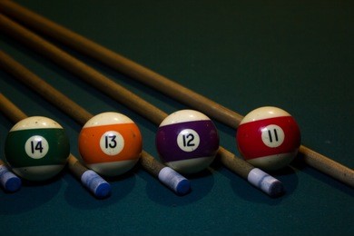 four billiard colorful balls with five cue on green billiard table