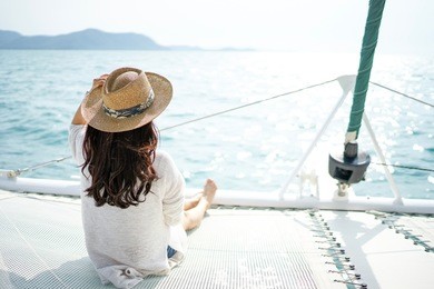 a lady with long hair wearing hat sitting on a luxurious white yacht