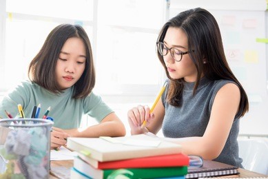 group of female asian chinese college students doing assignment at the table in classroom