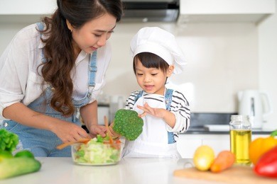 happy family in the kitchen. mother and child daughter are preparing the vegetables and fruit.