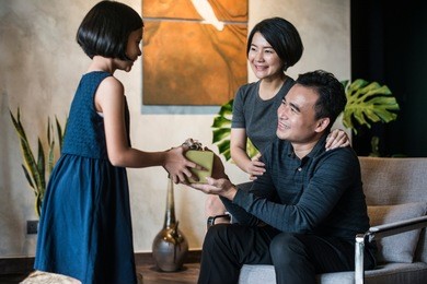 happy young asian girl giving present to her father.