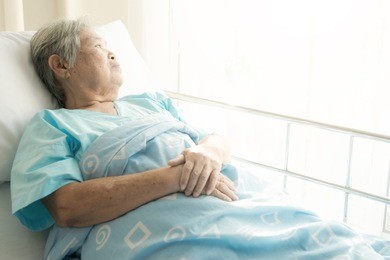 elderly patient alone in bed. alone and stress, missing her grand children. looking at window. very senior, old chinese woman.
