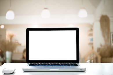 laptop with blank screen and wireless mouse on empty space desk white at cafe interior blurred background.