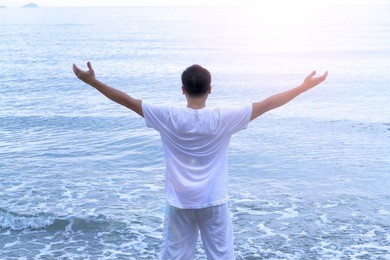 asaian senior citizen man in white easy dress spending his holiday vacation by relax in sunlight and soft breeze in a morning on the beach 