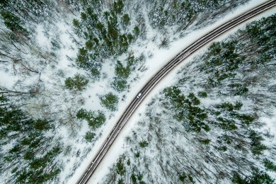 car rides on the road through the winter forest. road seen from the air. aerial view landscape. shooting from a drone 