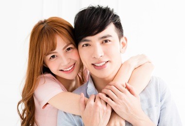happy young asian couple hugging in living room