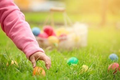 little girl gathering colorful egg in park. easter hunt concept