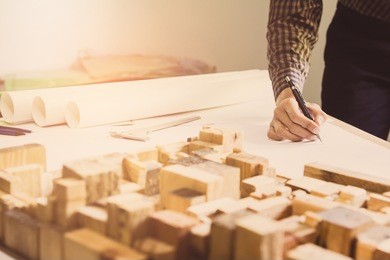 concept architects,engineer holding pen pointing equipment architects on the desk with a blueprint in the office, vintage, sunset light.selective focus