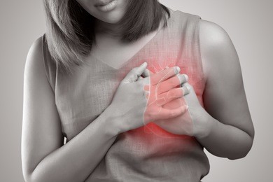 the photo of heart is on the woman's body, severe heartache, having heart attack or painful cramps, pressing on chest with painful expression.