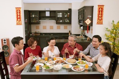 big asian family enjoying chinese new year celebration at home. scrolls wishing luck and wealth in the background