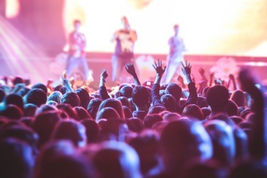 a crowded concert hall with scene stage lights, rock show performance, with people silhouette