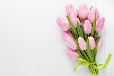 fresh pink tulip flowers bouquet on shelf in front of wooden wall.
